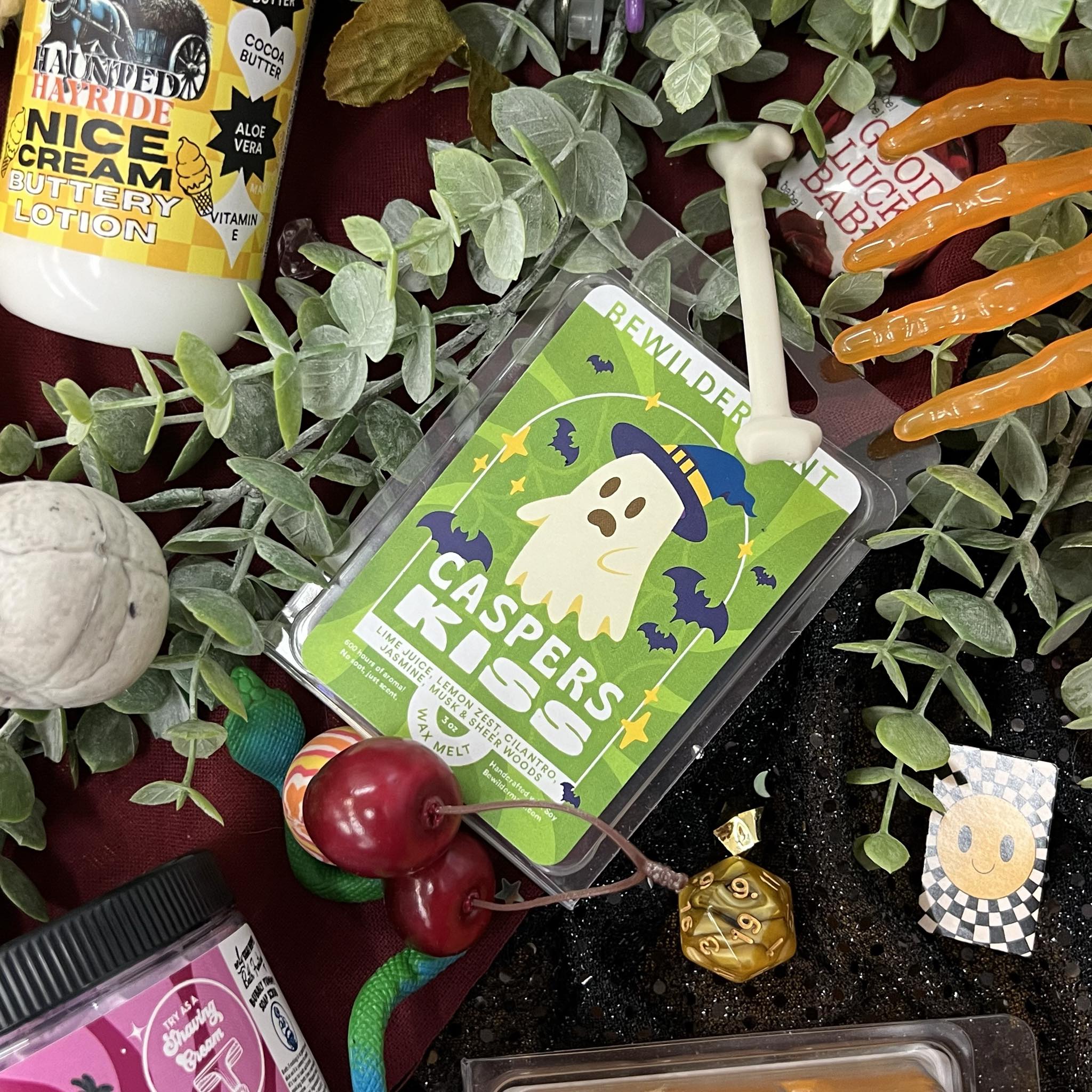 Green Caspers Kiss wax melts package with ghost and bat design surrounded by plants and Halloween-themed decorations.